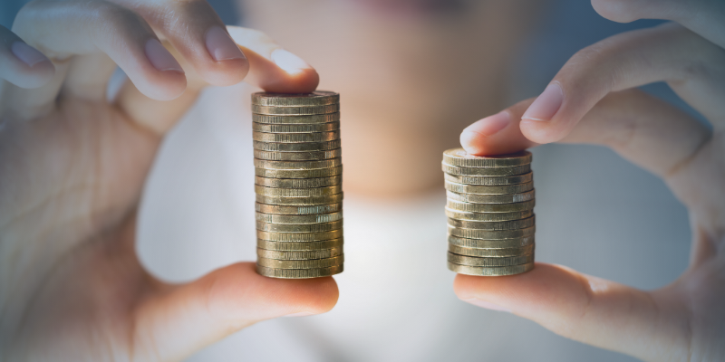  Close-up of two hands comparing stacked coins of different heights, illustrating pay differences and transparency challenges under the EU Pay Transparency Directive.